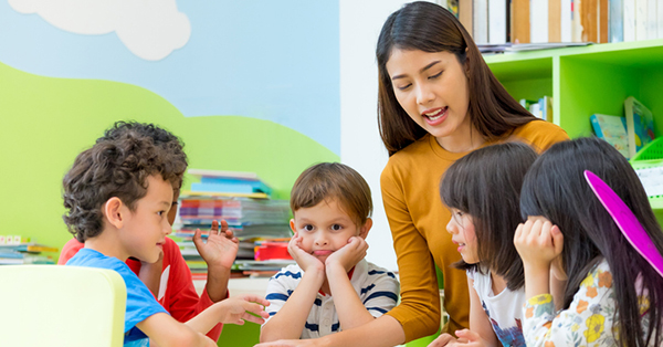 Asian female teacher teaching mixed race kids reading book in classroom,Kindergarten pre school concept