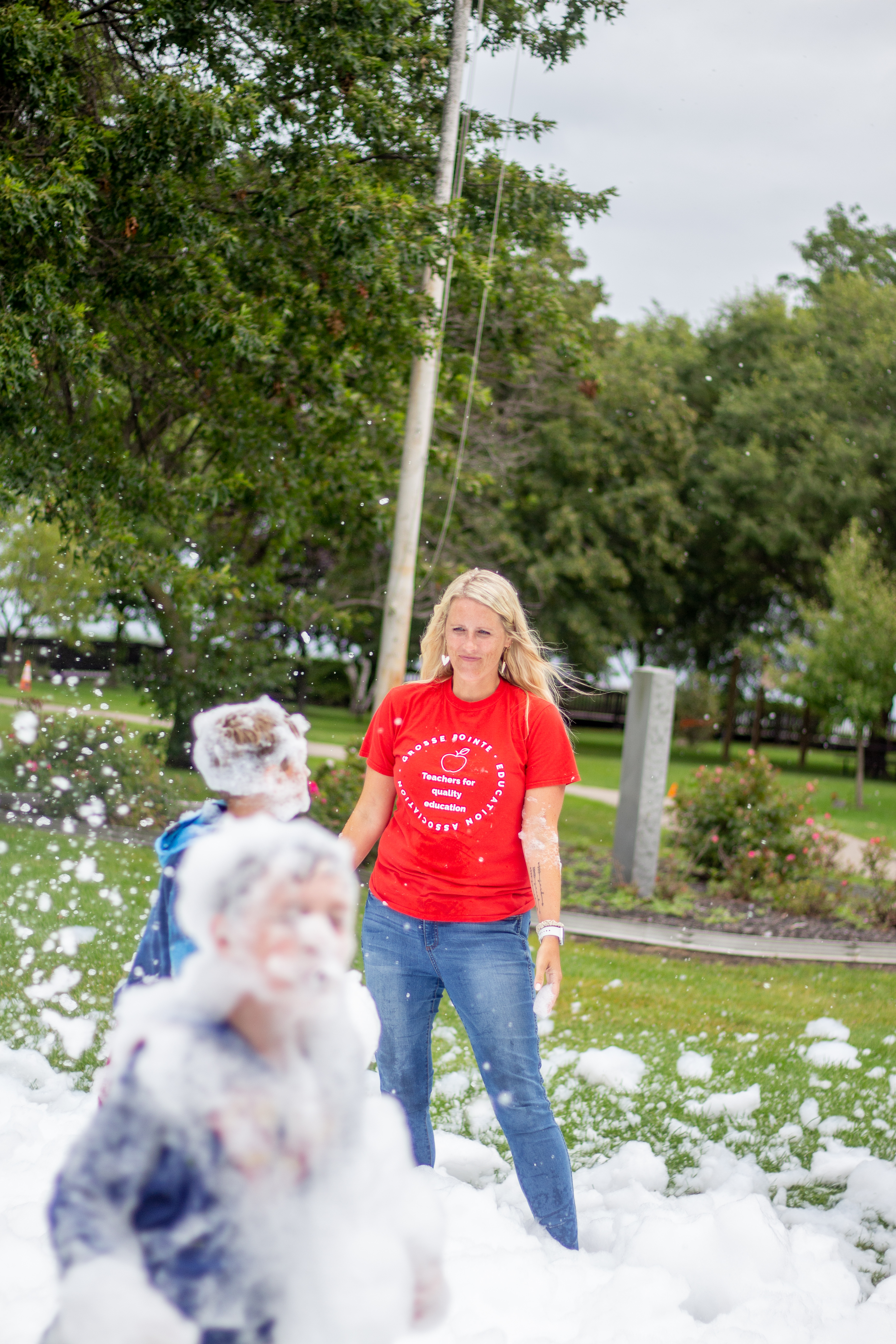 Photo of a teacher smiling at kids playing with bubbles and foam