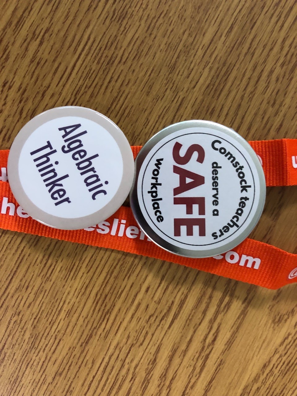 A photo of supportive buttons on a teacher's lanyard