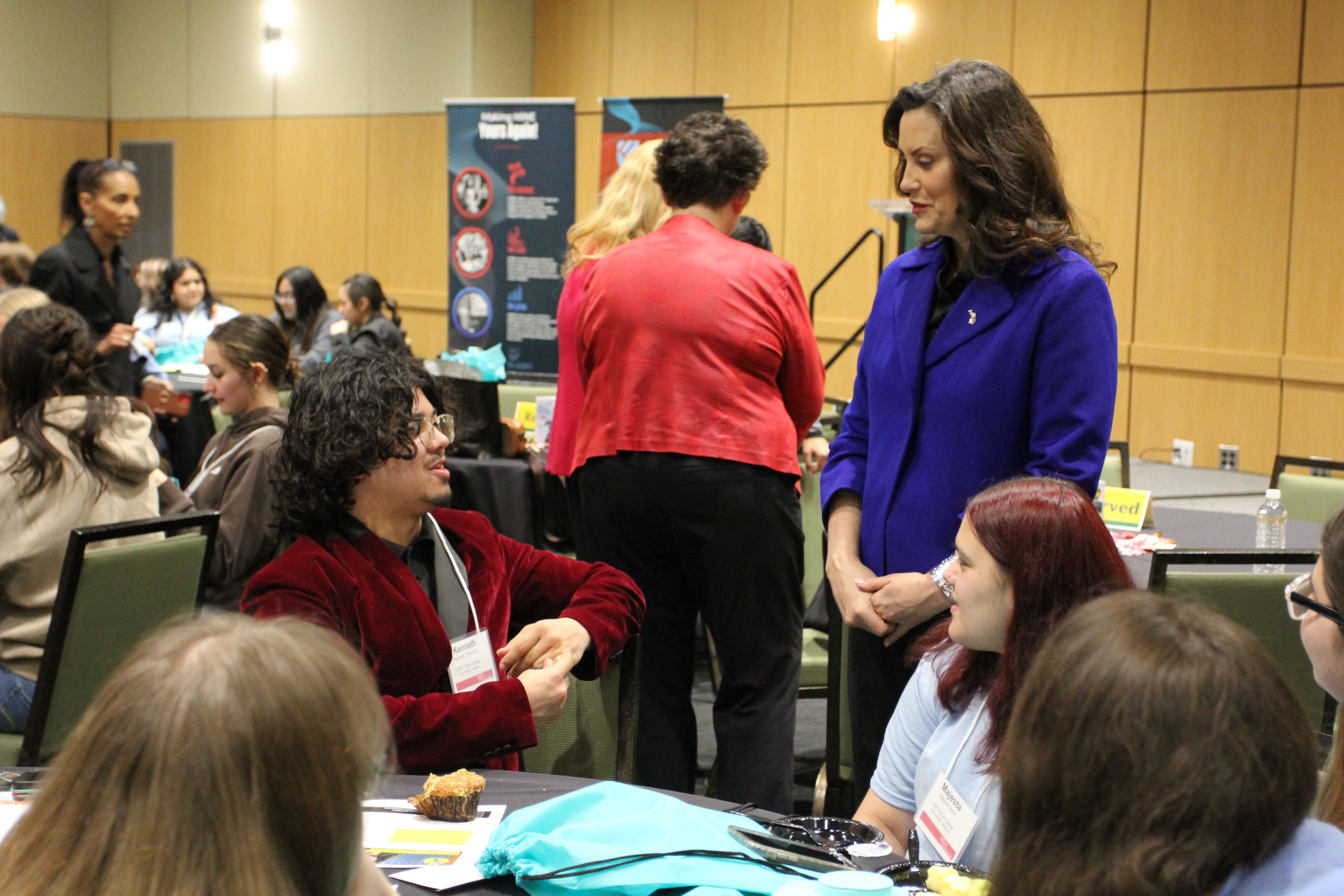 A photo of Gov. Whitmer chatting with a group of high school students interested in careers in education.