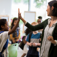A photo of a teacher and student giving high fives.